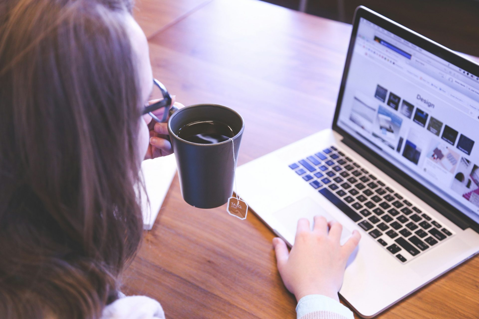 Woman sipping tea while browsing online.